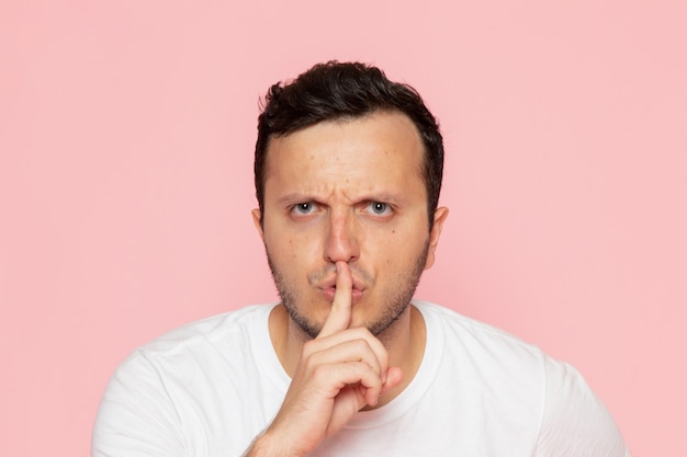 A front view young male in white t-shirt posing with silence gesture