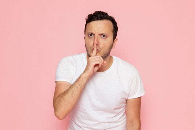 A front view young male in white t-shirt showign silence sign