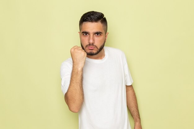 A front view young male in white t-shirt showing his fist