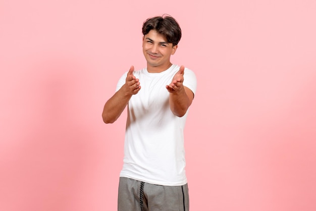 Front view young male in white t-shirt smiling on pink background