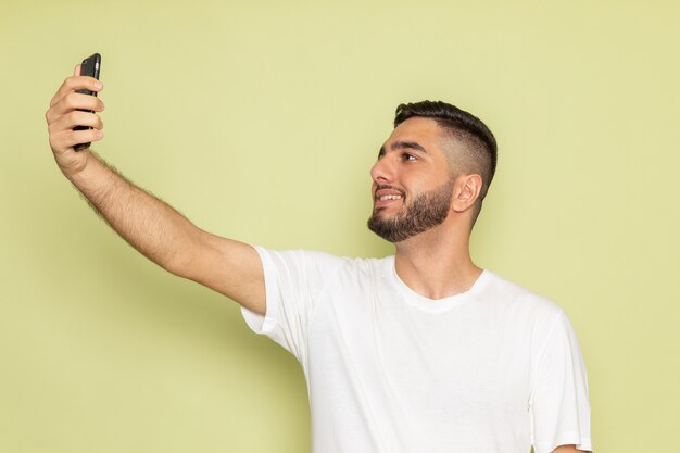 A front view young male in white t-shirt taking a selfie