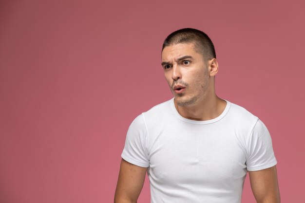 Front view young male in white t-shirt with surprised expression on pink background