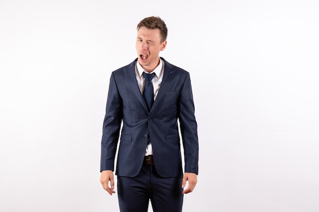 Front view young male winking in elegant classic suit on white background