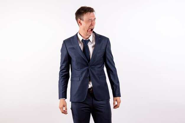 Front view young male winking in funny manner in classic strict suit on white background