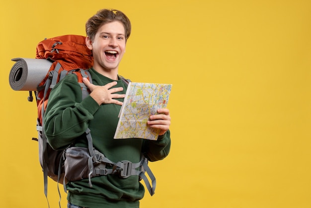 地図を保持しているバックパックを持つ若い男性の正面図