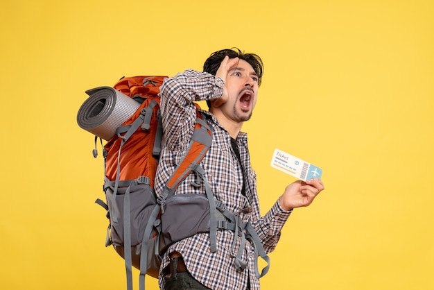 Front view young male with backpack holding ticket screaming on yellow 