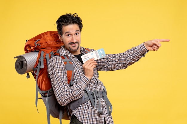 Front view young male with backpack holding ticket on a yellow 