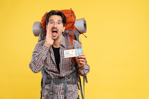 Front view young male with backpack holding ticket on a yellow 