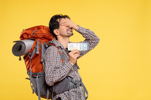 Front view young male with backpack holding ticket on yellow 