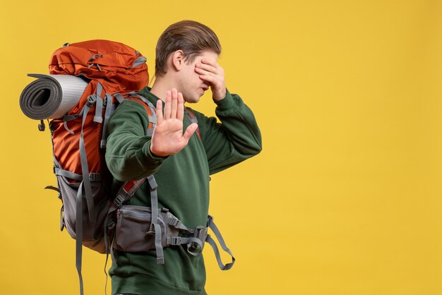 ハイキングの準備をするバックパックを持つ若い男性の正面図
