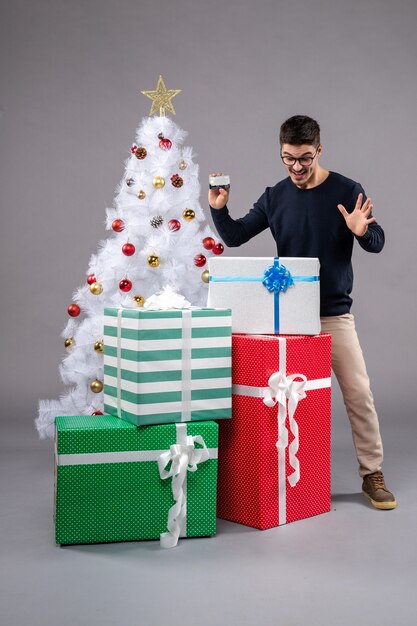 Front view young male with bank card and presents on grey