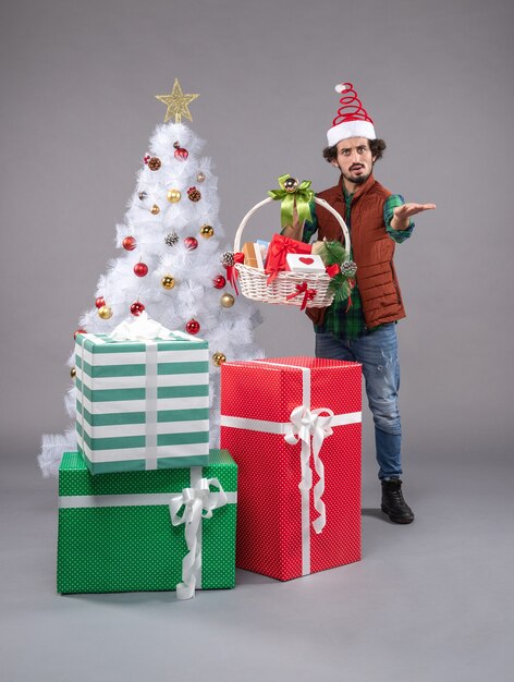 Front view young male with basket around presents on grey floor human new year christmas
