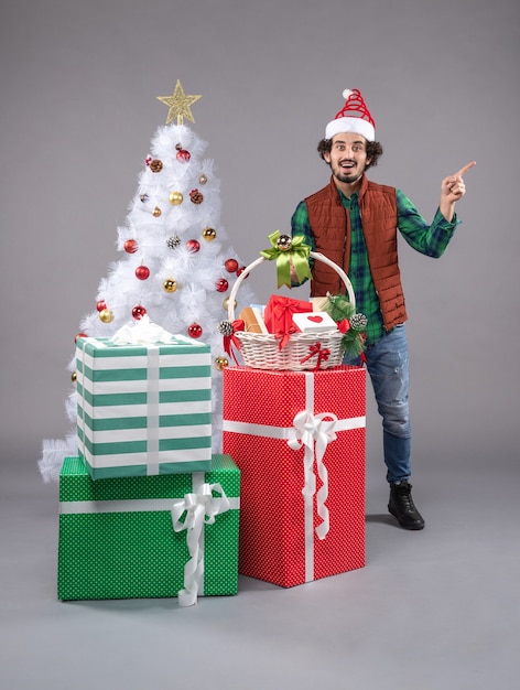 Front view young male with basket around presents on grey floor new year christmas human