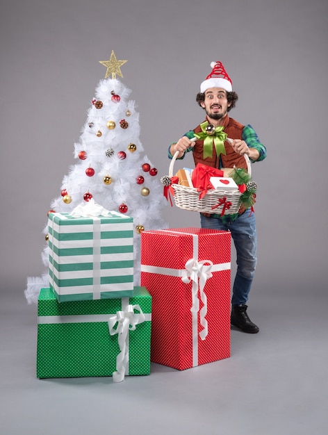 Front view young male with basket around presents on a grey 