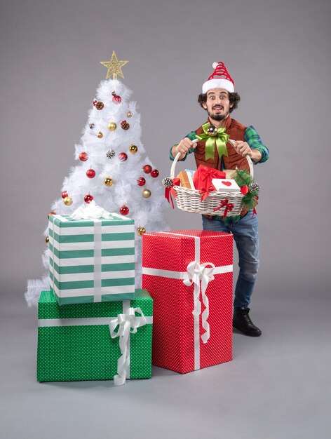 Front view young male with basket around presents on a grey 