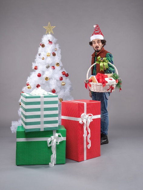 Front view young male with basket around presents on a grey 