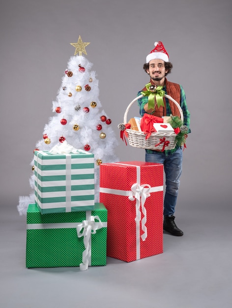 Front view young male with basket around presents on grey 