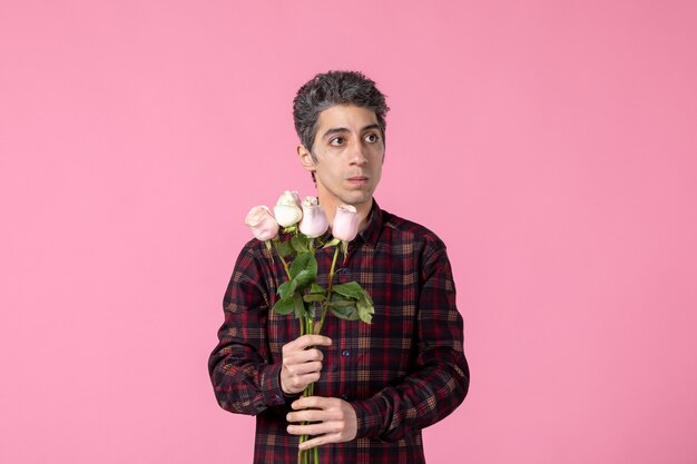 Front view young male with beautiful pink roses on pink wall