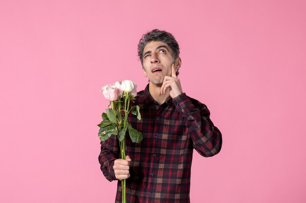 Front view young male with beautiful pink roses on pink wall