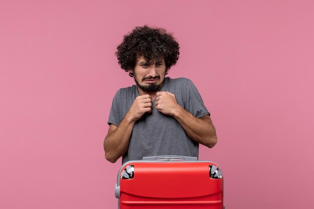 Front view young male with big red bag preparing for trip and posing on a pink space