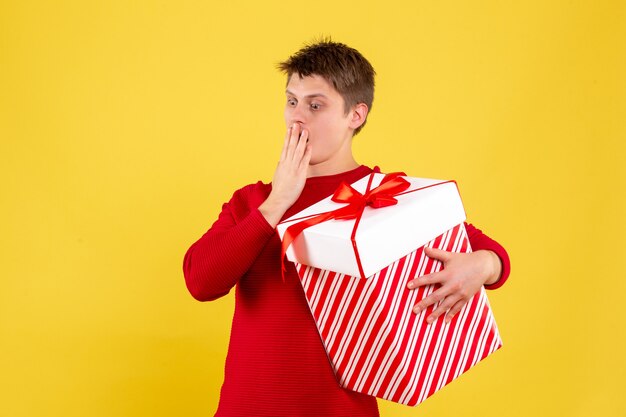 Front view young male with big xmas present on yellow background