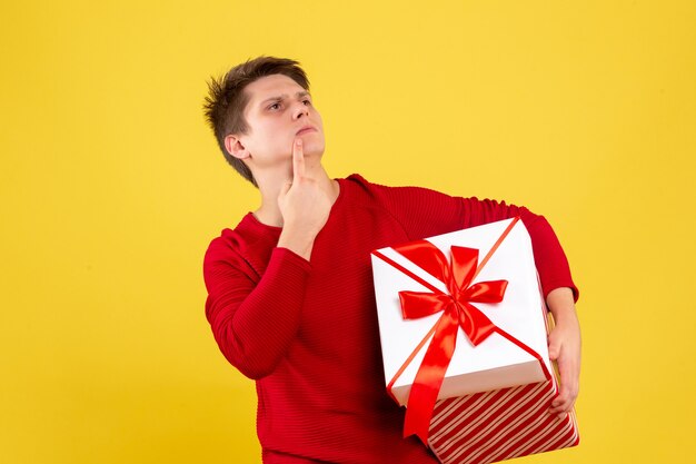 Front view young male with big xmas present on yellow background