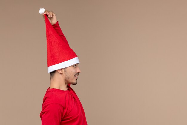 Free photo front view young male with christmas cape on brown desk holiday christmas emotion