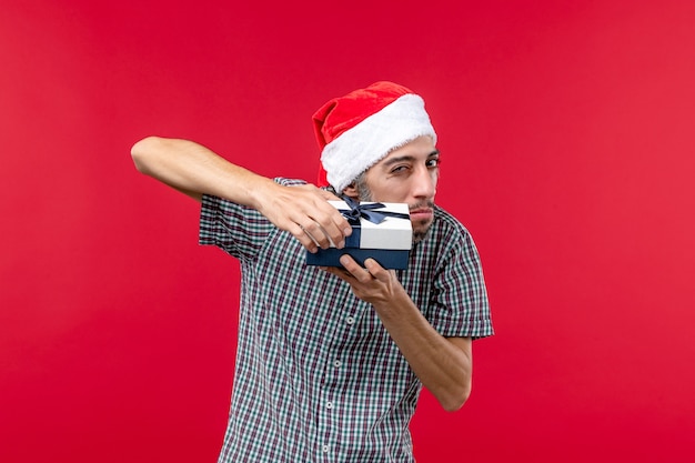 Front view of young male with christmas present on red