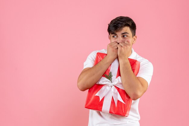 Front view young male with christmas present scared on pink background