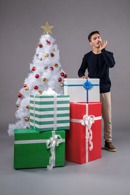 Front view young male with christmas presents on grey desk new year gift xmas