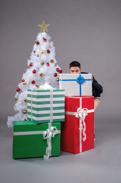 Front view young male with christmas presents on grey