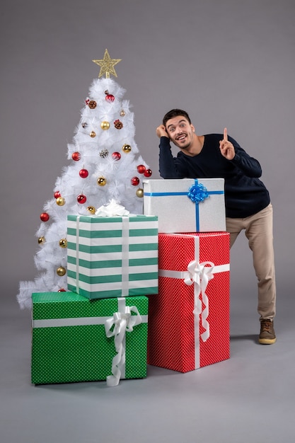 Front view young male with christmas presents on grey