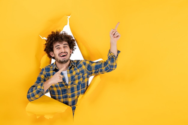 Free photo front view young male with curly hair on a yellow ripped background