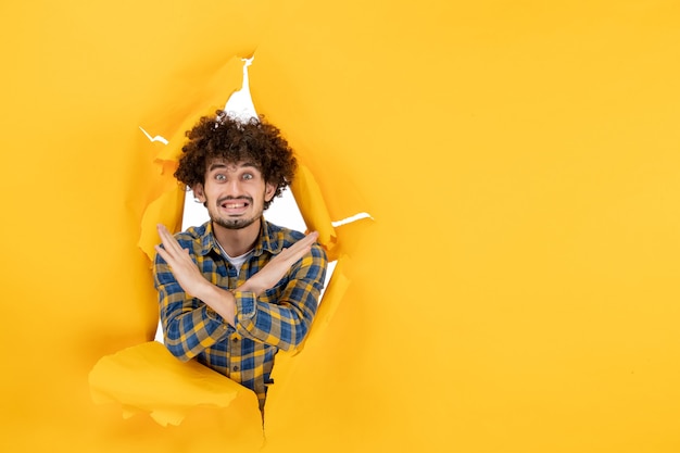 Free photo front view young male with curly hair on yellow ripped background