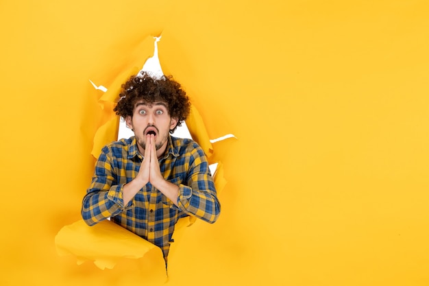 Free photo front view young male with curly hair on yellow ripped background