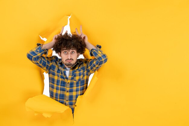 Front view young male with curly hair on yellow ripped background