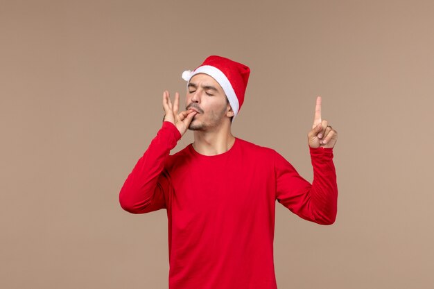 Вид спереди молодого мужчины с довольным лицом на коричневом фоне, праздничные рождественские эмоции
