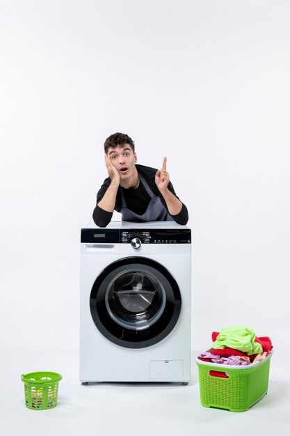 Front view of young male with dirty clothes and washer on white wall