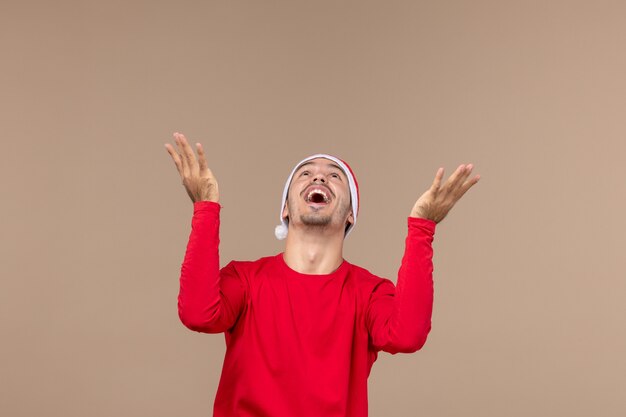 Вид спереди молодого мужчины с возбужденным выражением лица на коричневом столе эмоции рождественских праздников