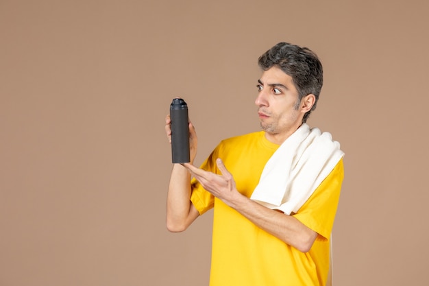 Free photo front view young male with foam and towel preparing to shave his face on pink background