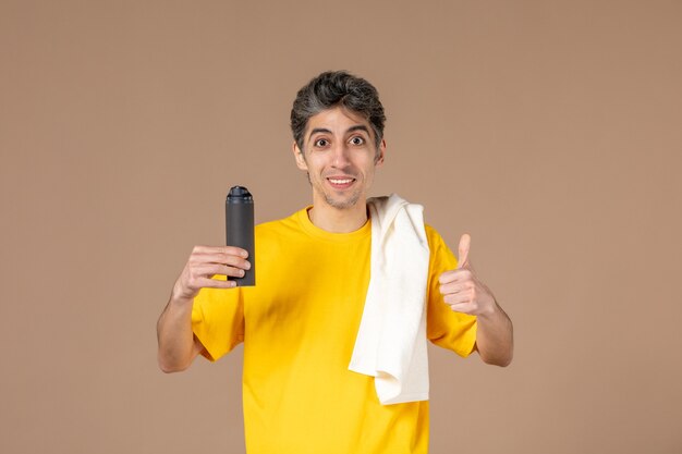 front view young male with foam and towel preparing to shave his face on pink background