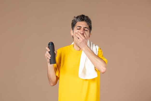 front view young male with foam and towel preparing to shave his face on pink background