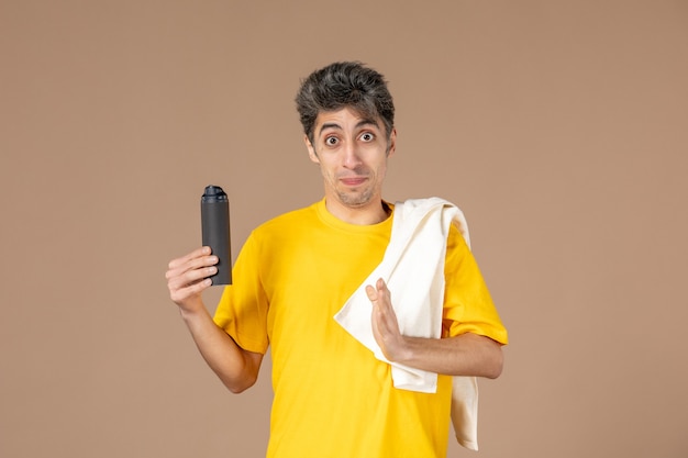 ピンクの背景に彼の顔を剃る準備をしている泡とタオルを持つ若い男性