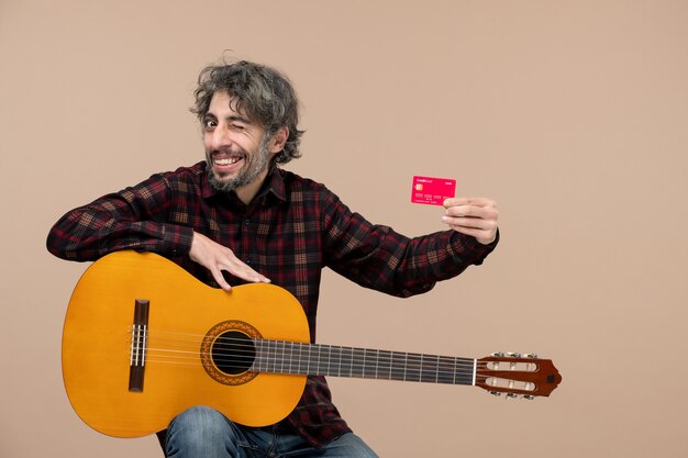 분홍색 벽에 은행 카드를 들고 기타를 들고 있는 젊은 남성의 전면 모습