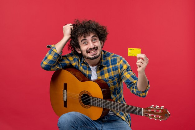 빨간 벽 컬러 공연 음악가 라이브 콘서트 밴드 돈에 기타를 들고 은행 카드를 들고 전면 보기 젊은 남성