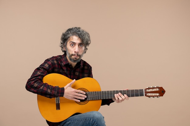 Front view of young male with guitar on pink wall