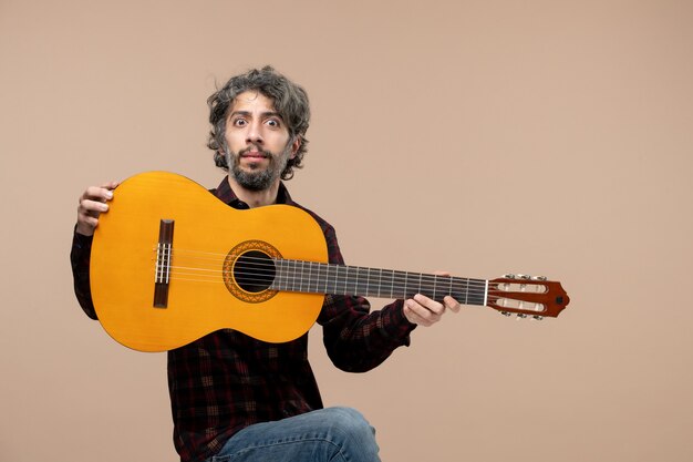 분홍색 벽에 기타를 든 젊은 남성의 전면 모습