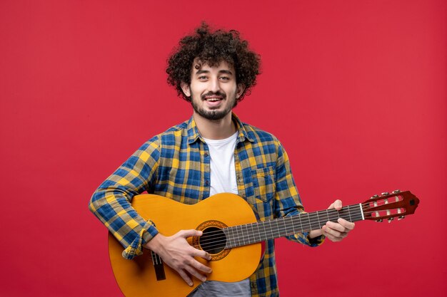 Front view young male with guitar on red wall concert live play color band applause music musician