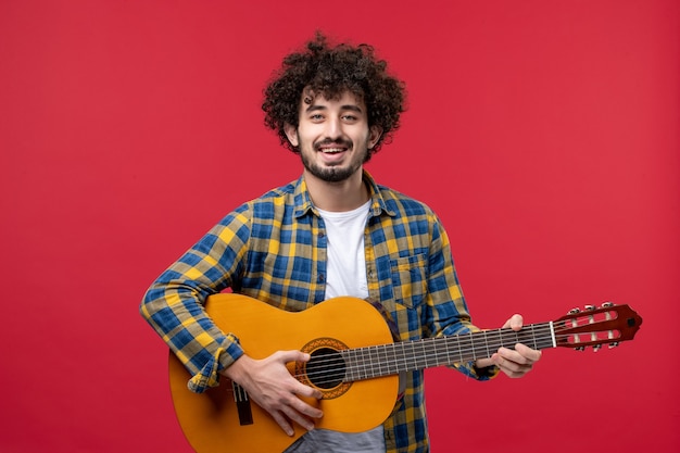 Free photo front view young male with guitar on red wall performance concert live play color band applause music musician