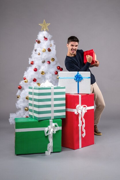 Front view young male with holiday presents on grey desk human new year xmas gift